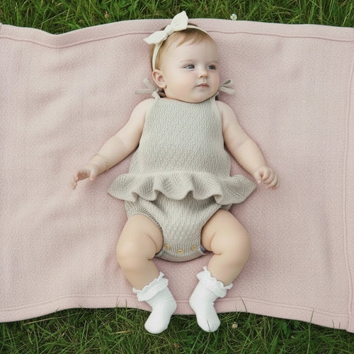 Knitted baby romper with ruffled bottom on a white background