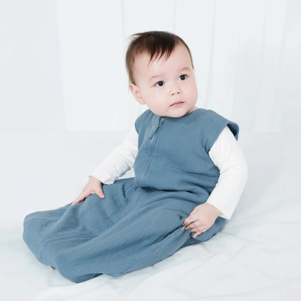 Baby wearing a blue and white outfit sitting on a white surface