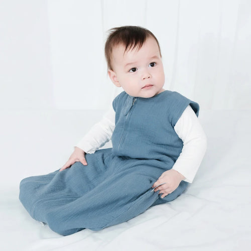 Baby wearing a blue and white outfit sitting on a white surface
